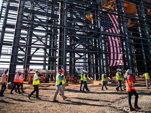 Foto: Aurubis: Gerüst einer Halle die sich gerade in Konstruktion befindet, die USA Flagge und Menschen sind auf der Baustelle zu sehen