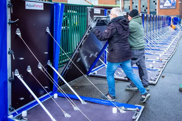 Foto: Aurubis: Zwei Männer eine eine Platte hoch, die gegen Hochwasser schützen soll
