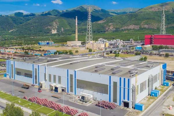 Foto: Aurubis: Eine grosse weisse Lagerhalle von aussen mit blauen Streifen, Luftaufnahme