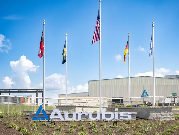 Foto: Aurubis: Gebaeude mit mehreren Fahnen verschiedener Laender vor einem blauen Himmel